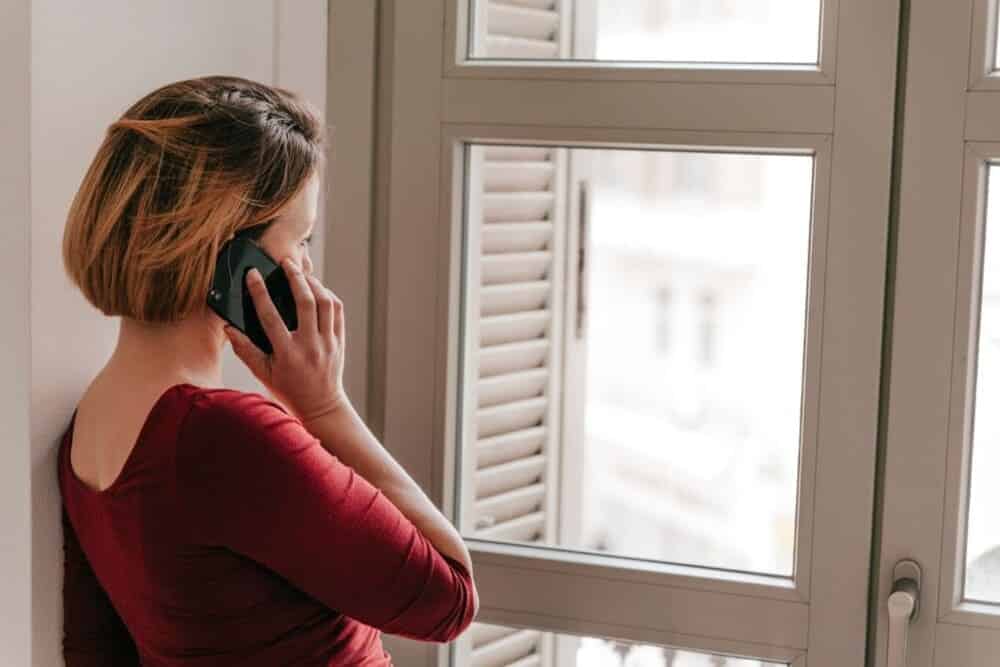 chica hablando por teléfono frente a ventana