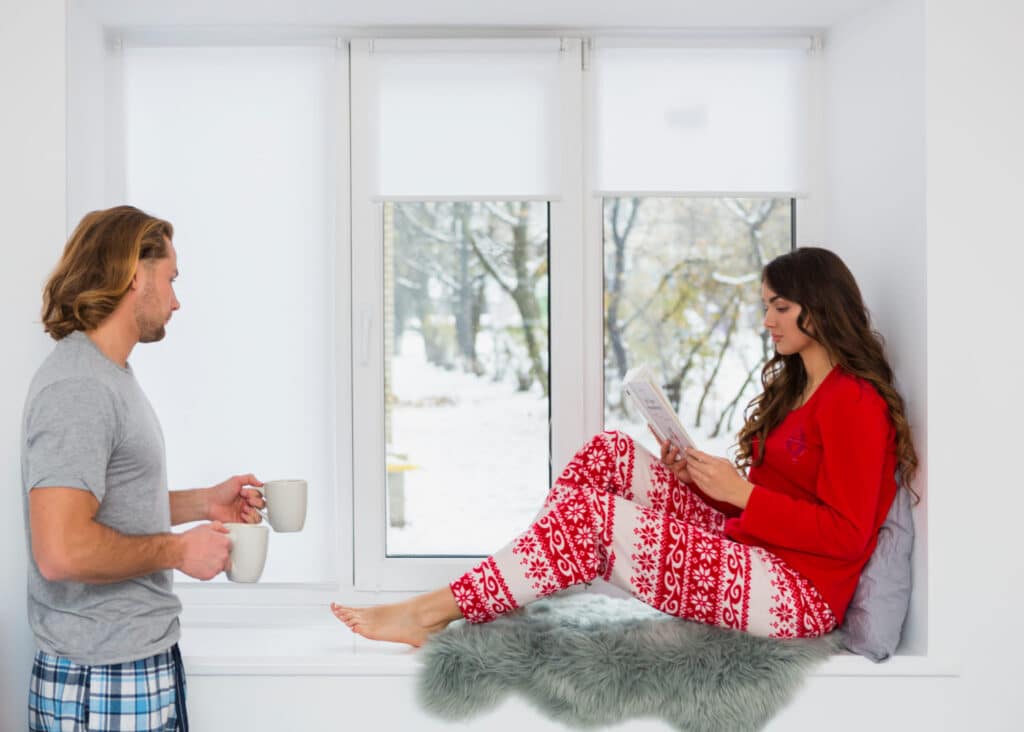 hombre mujer sentados junto a ventana con pijama ropa comoda taza de cafe interior hogar clima frio invierno